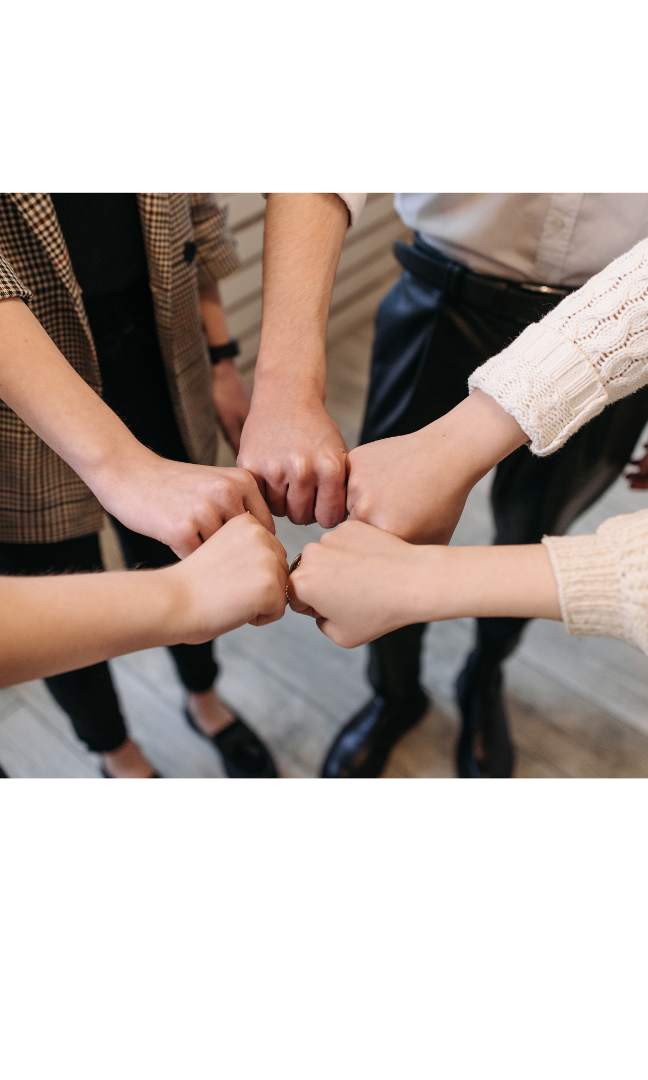 A group of five people putting their fists together in a circle.